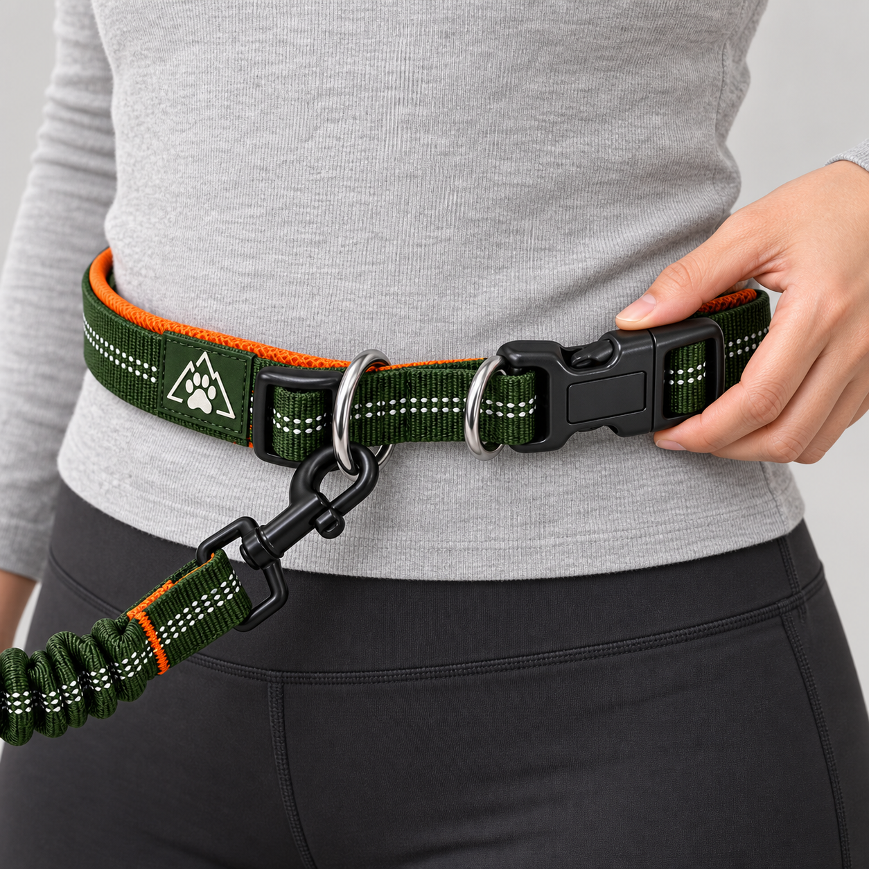 Hand adjusting the forest-green and orange KIBOPAW waist leash buckle